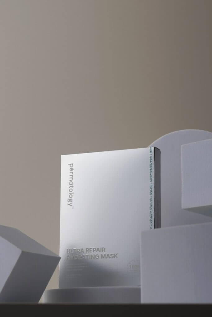 Two white rectangular skincare product boxes standing upright against a beige wall, one slightly behind the other.